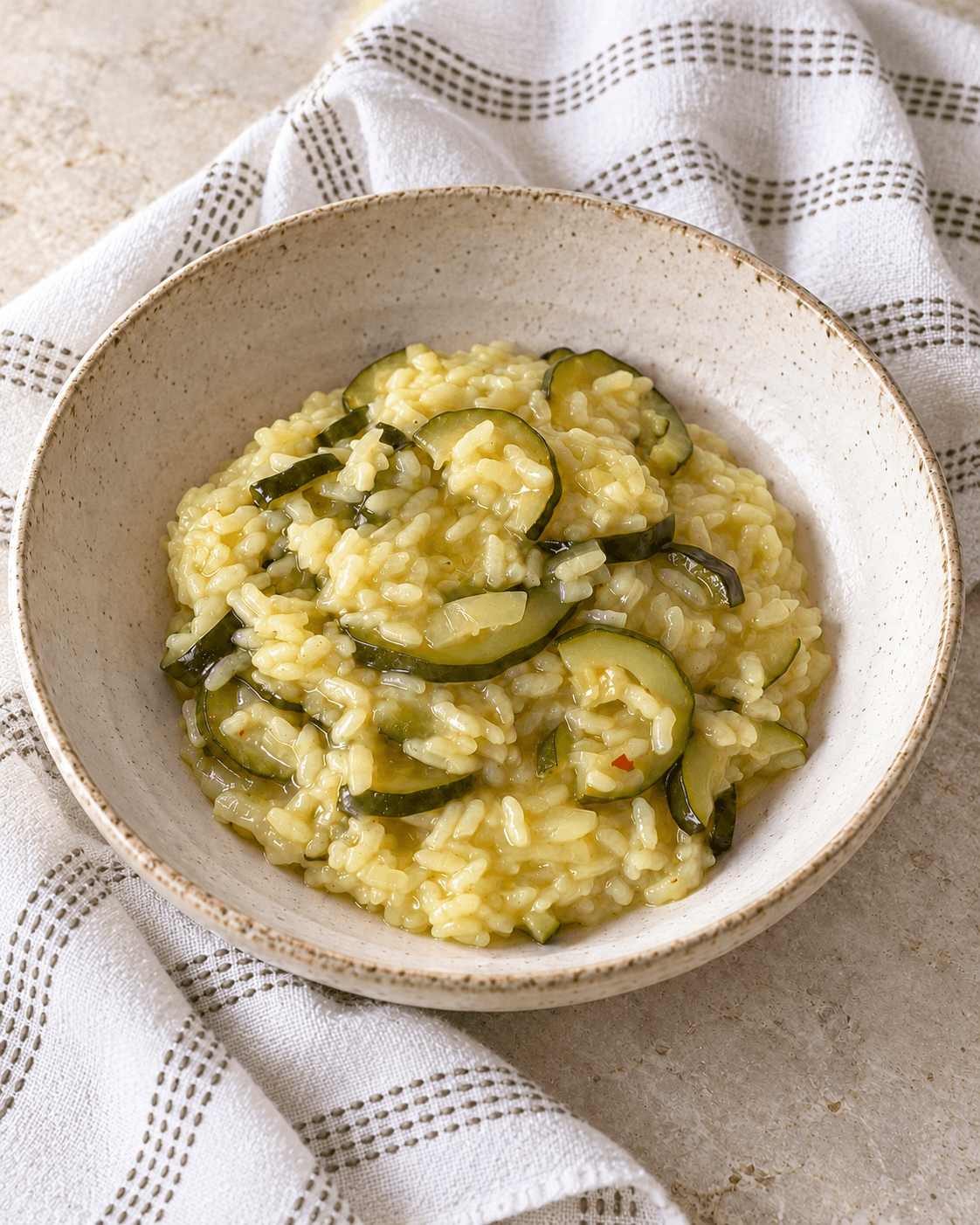 Zucchini risotto with thin slices of zucchini and flecks of chilli in a shallow bowl